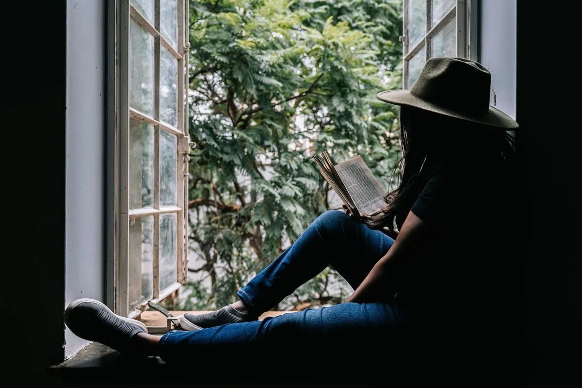 Picture of Kui Kabala reading a book by a windon